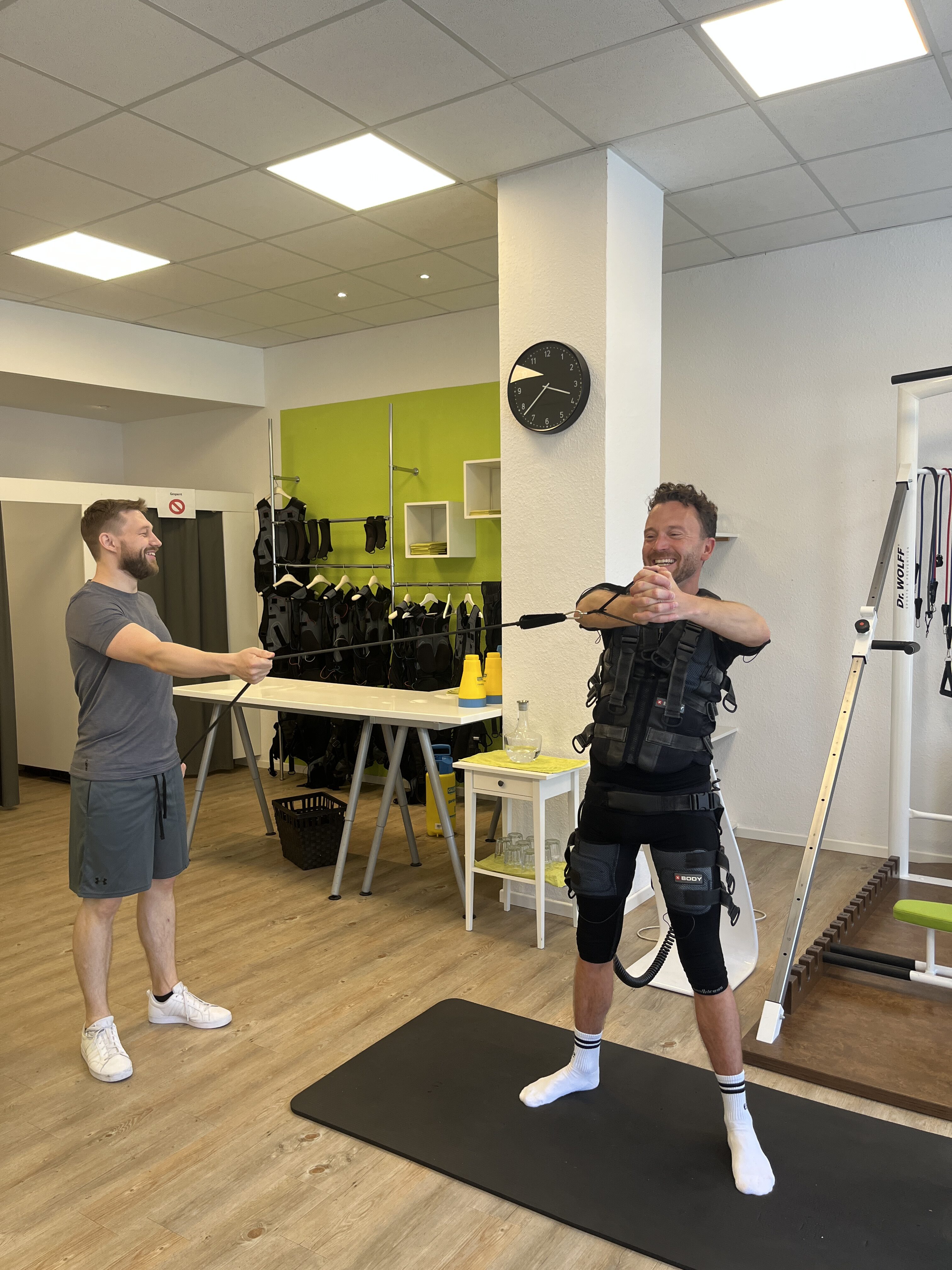 Ein Mann trainiert mit einem Trainer in einem Fitnessstudio. Sie wirken konzentriert.